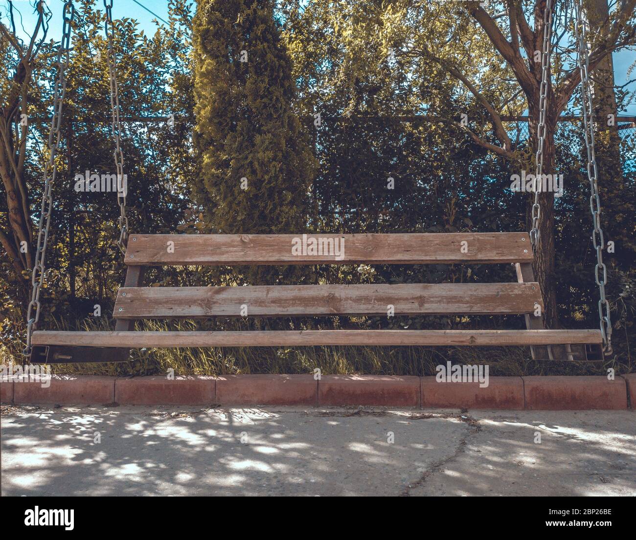 Un grande altalena in un parco con alberi e recinzione. Foto Stock