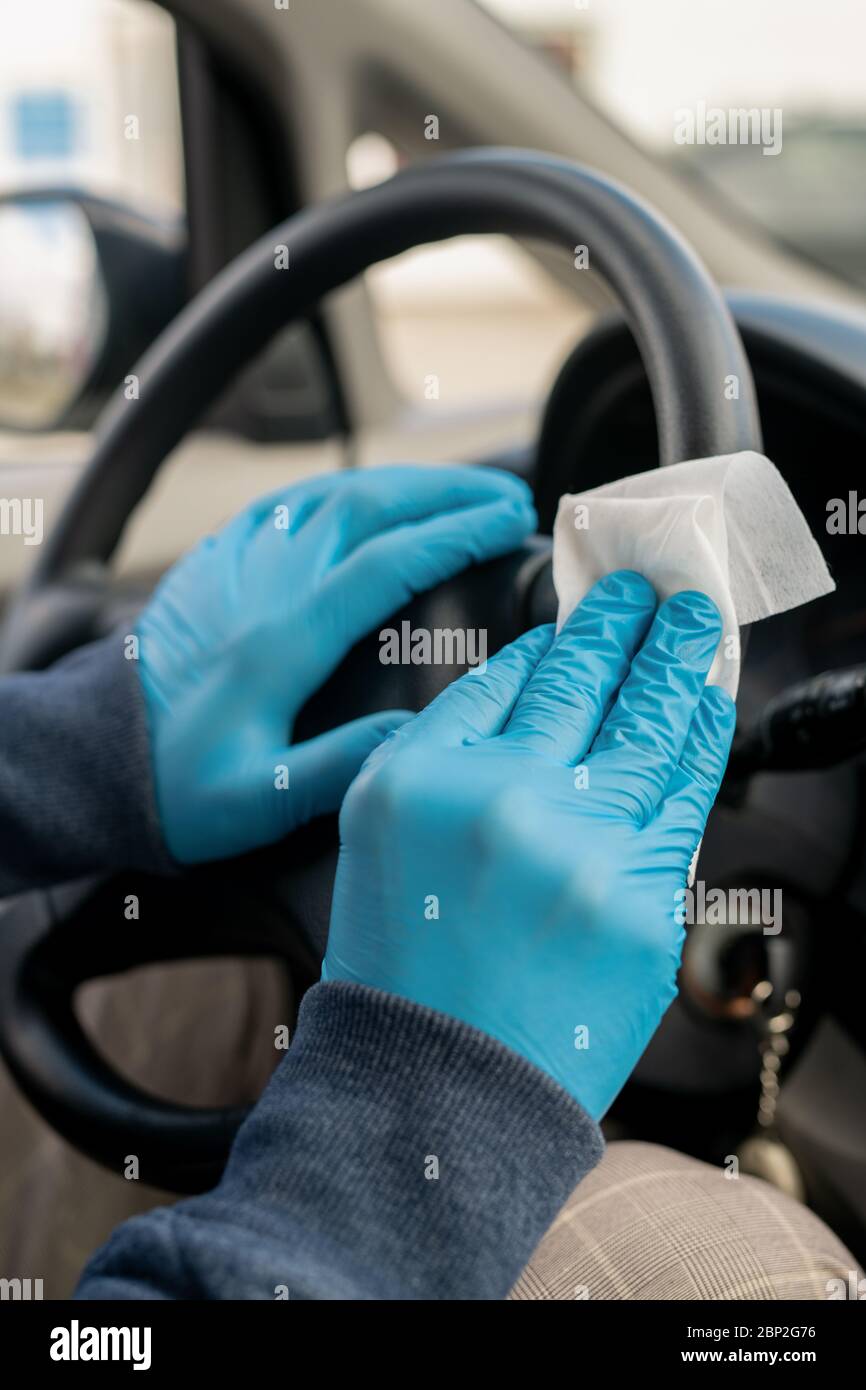 Mani gualcate di giovane uomo che pulisce con wet wipe prima di guidare a casa dopo aver visitato il supermercato o altro luogo pubblico Foto Stock