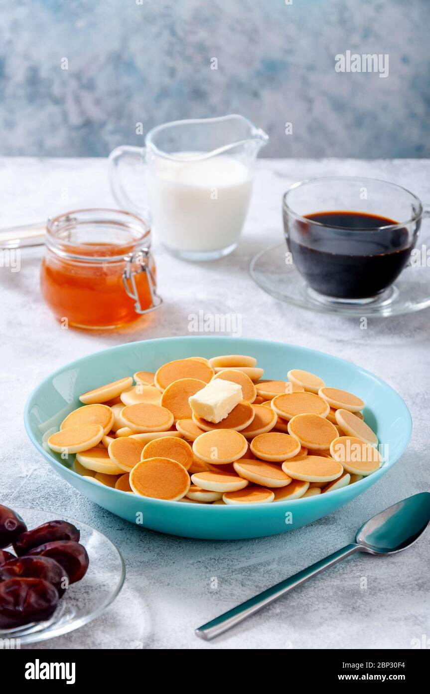 Pancake di cereali con burro in ciotola su tavola di pietra grigia. Cucina alla moda. Foto Stock