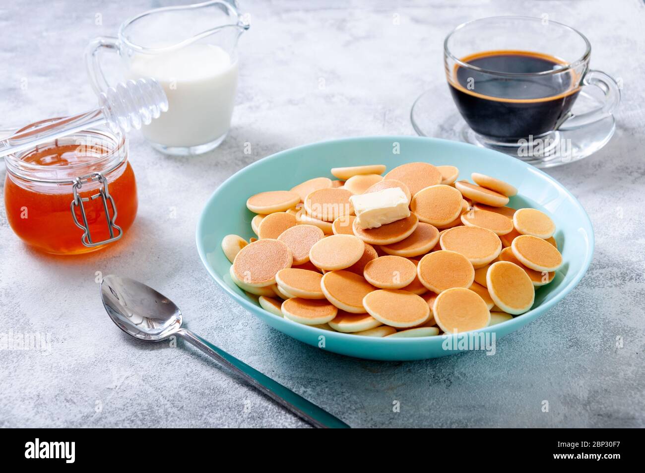 Pancake di cereali con burro in ciotola su tavola di pietra grigia. Cucina alla moda. Foto Stock