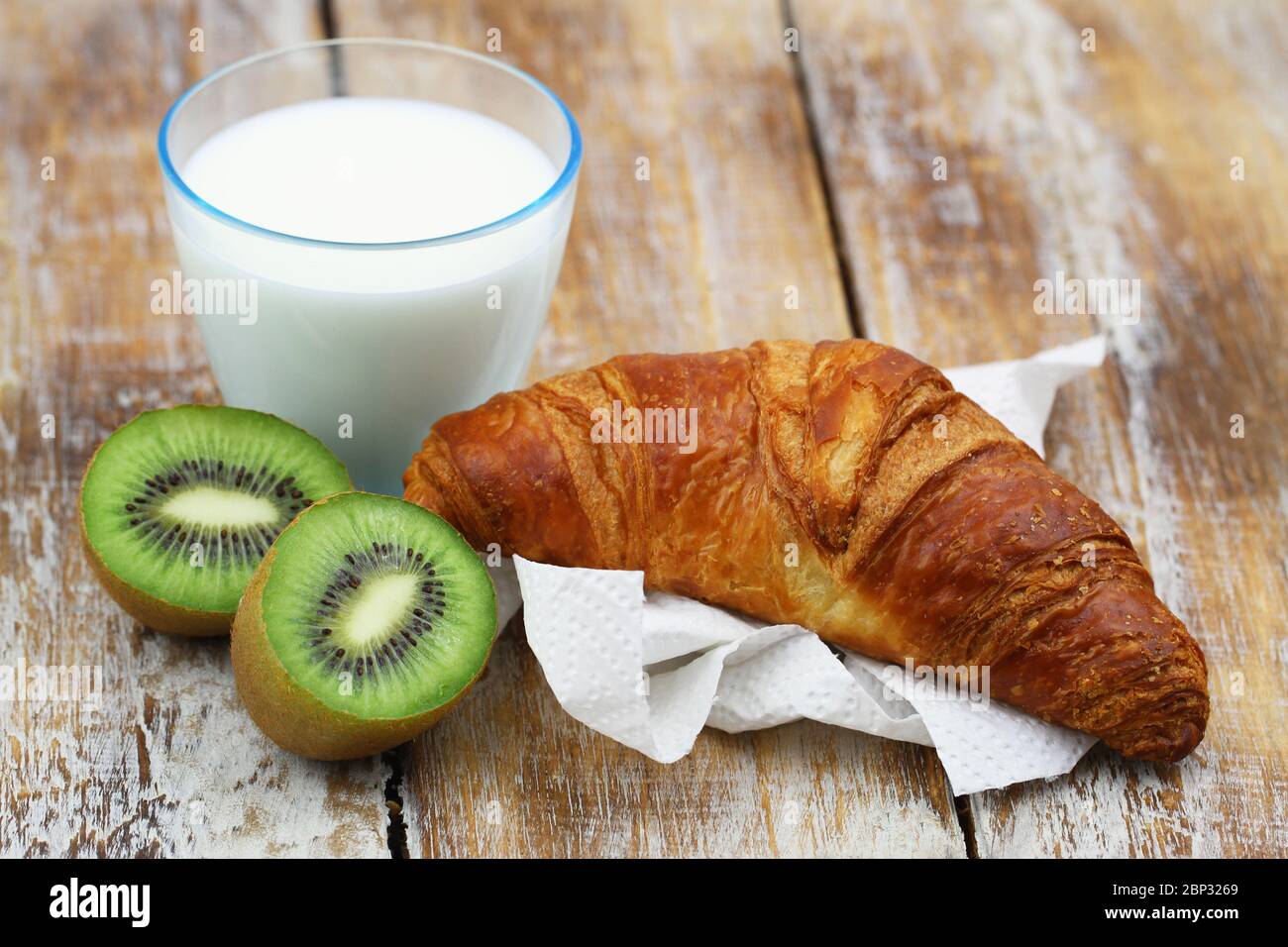 Colazione semplice: Croissant francese, kiwi e un bicchiere di latte Foto Stock