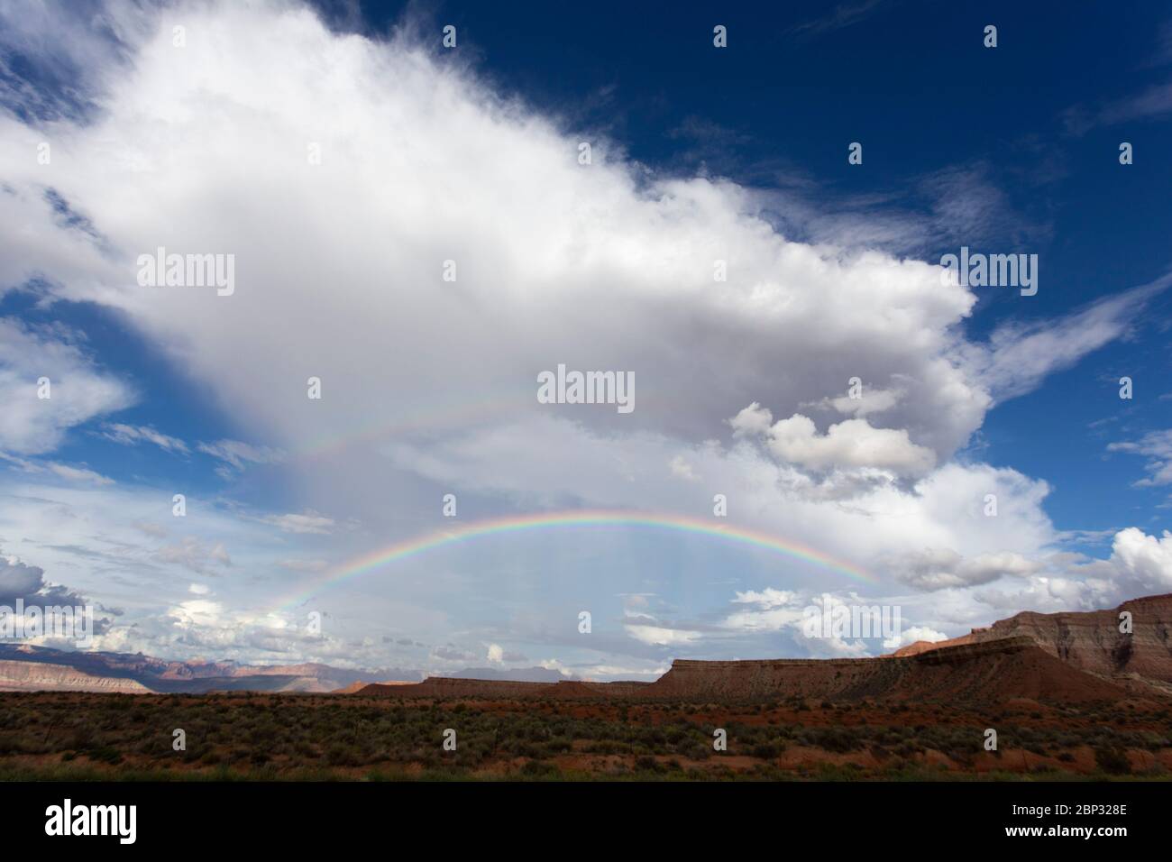 Arcobaleno sotto una nuvola thunderhead contro il paesaggio rosso dell'uragano, Utah Foto Stock