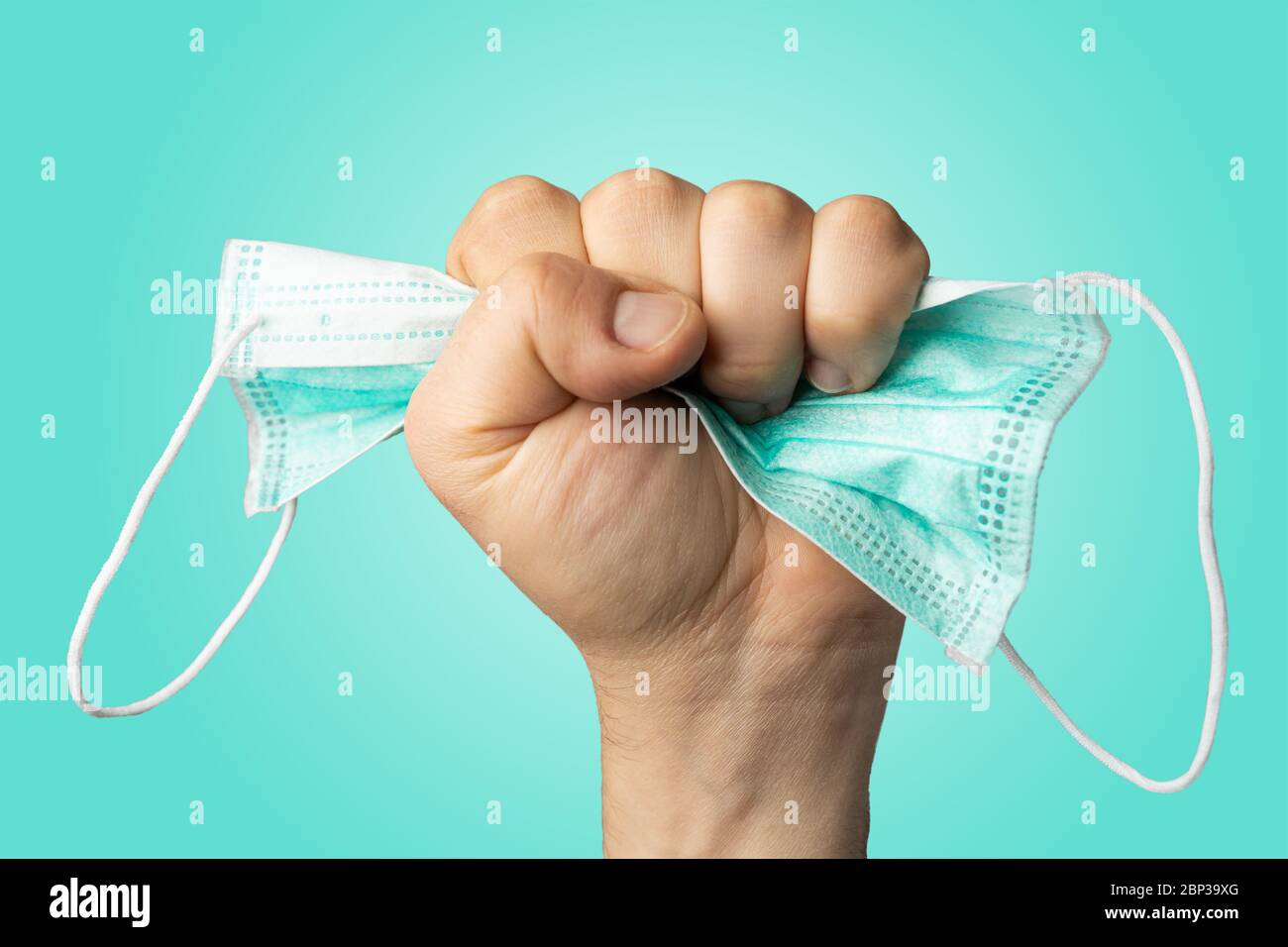 Uomo caucasico che tiene in mano una maschera protettiva schiacciata. Fine del concetto astratto pandemico o di quarantena. Foto Stock