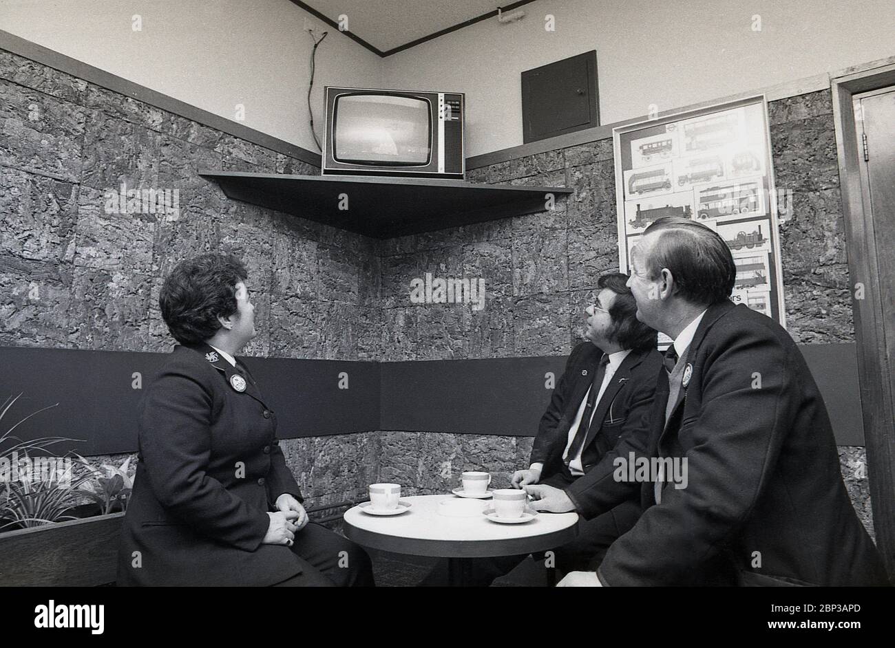 Interno, stanza di riposo del personale dell'autobus New Cross, Londra del sud, Inghilterra, 1974, l'immagine mostra tre membri dell'equipaggio in uniforme che hanno una pausa e una tazza di tè e che guardano una piccola televisione portatile. Foto Stock