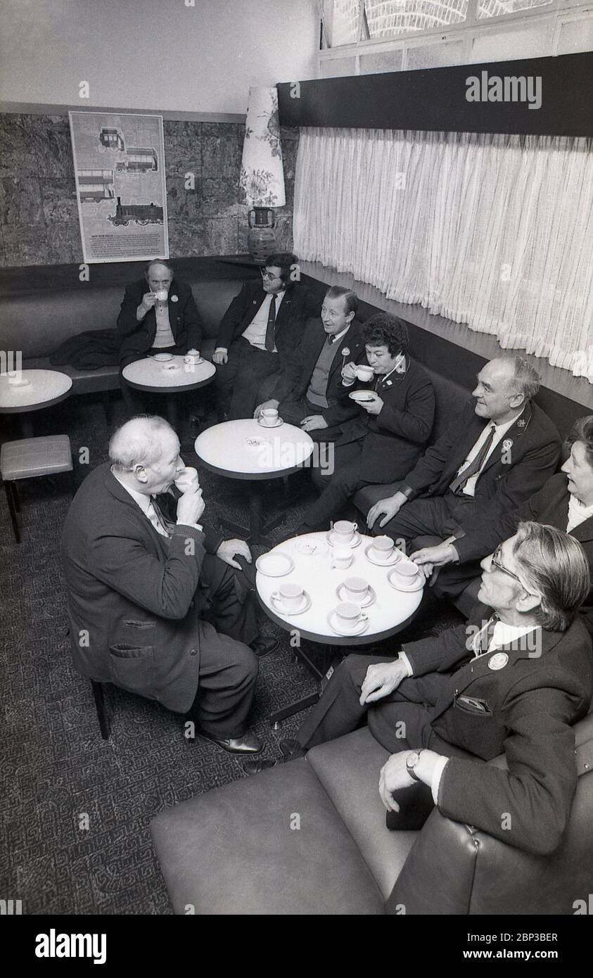 Immagine interna che mostra i lavoratori in uniforme degli autobus seduti insieme in una sala di riposo presso il deposito degli autobus di New Cross, a sud-est di Londra, Inghilterra, 1974. L'equipaggio dell'autobus sta facendo una pausa, una tazza di tè, un fumo e una chiacchierata con i colleghi di lavoro. Originariamente un deposito di tram, New Cross fu convertita in un depoet di autobus n 1952 ed era uno dei più grandi garage di autobus di Londra. Foto Stock