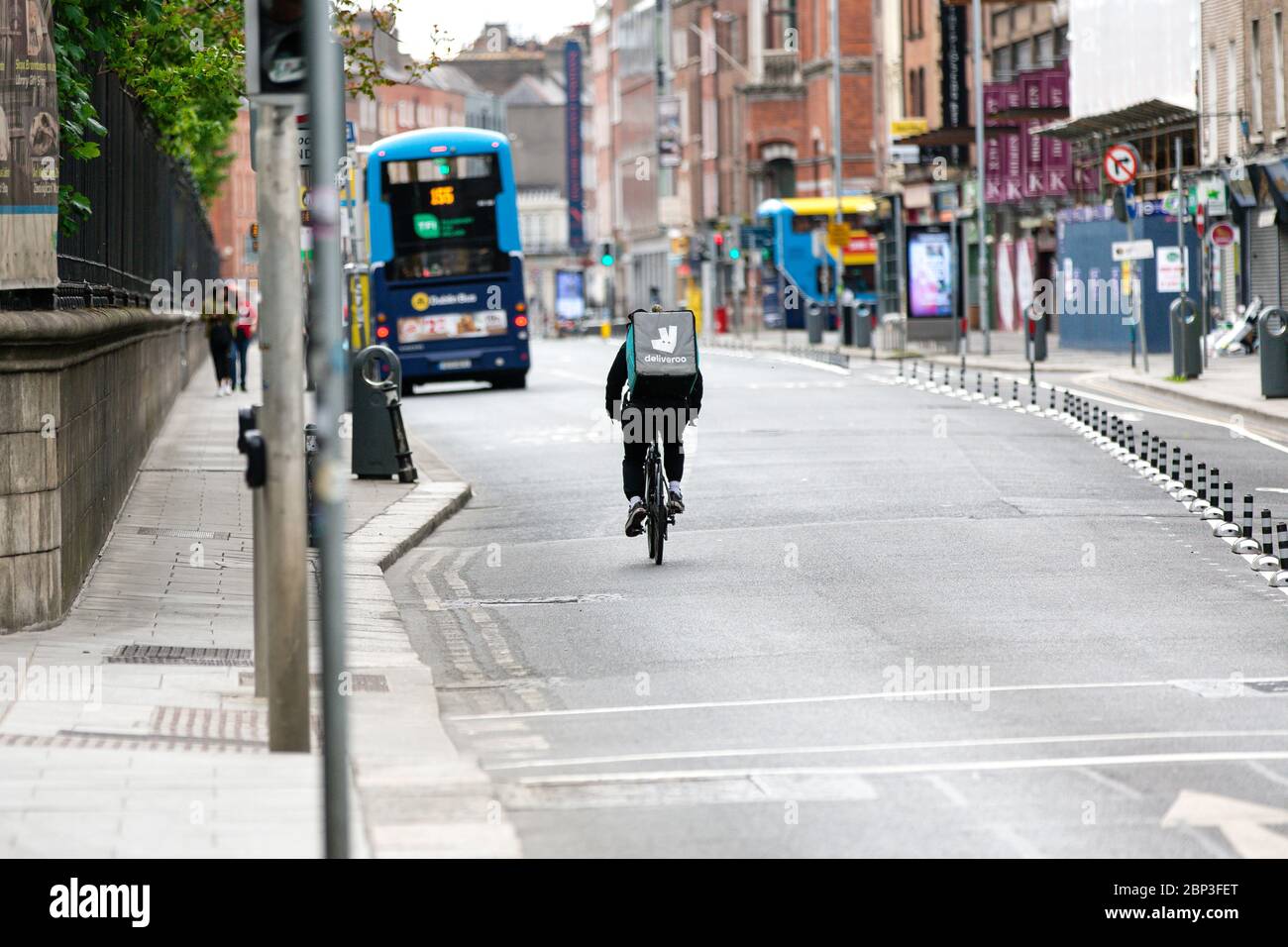 Dublino, Irlanda. Maggio 2020. Deliveroo food che offre ciclista che attraversa vuota Nassau Street nel centro di Dublino durante la pandemia di Covid-19. Foto Stock