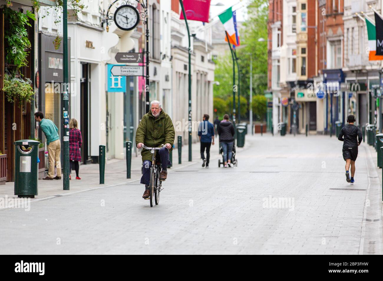 L'uomo anziano pedalando attraverso una tranquilla Grafton Street nel centro di Dublino, mentre la caduta dei piedi precipita a causa della pandemia del coronavirus. Covid-19 in Irlanda. Foto Stock
