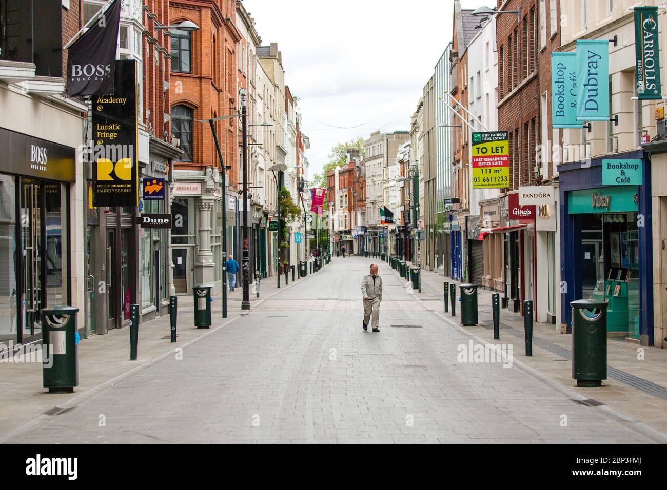 Uomo anziano che cammina attraverso Grafton Street deserta nel centro di Dublino, mentre la caduta dei piedi precipita a causa della pandemia di coronavirus. Covid-19 in Irlanda. Foto Stock