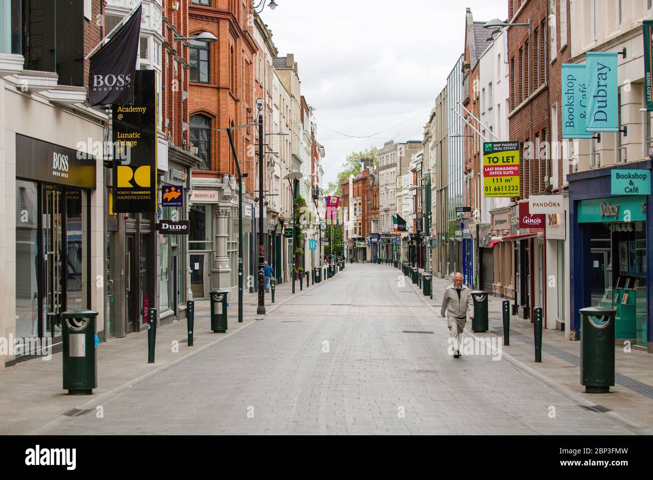 Uomo anziano che cammina attraverso Grafton Street deserta nel centro di Dublino, mentre la caduta dei piedi precipita a causa della pandemia di coronavirus. Covid-19 in Irlanda. Foto Stock
