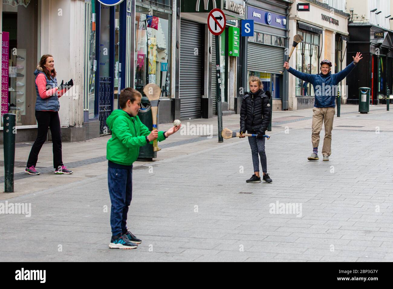 La famiglia gioca a fare un'esultante sulla deserta Grafton Street nel centro di Dublino, mentre le aziende e i negozi rimangono chiusi e i calci piovono a causa del Covid-19. Foto Stock