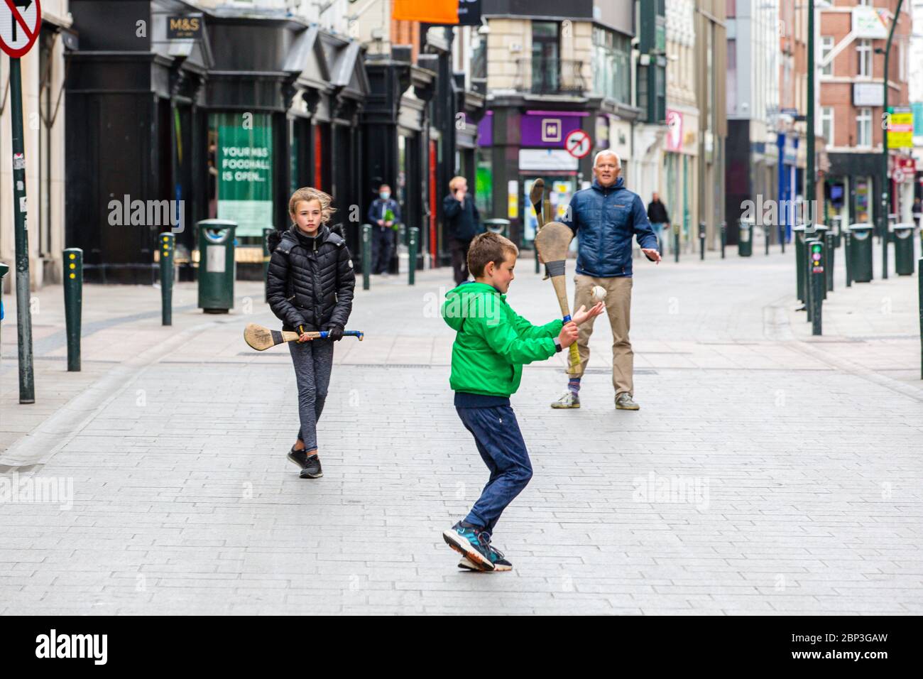 La famiglia gioca a fare un'esultante sulla deserta Grafton Street nel centro di Dublino, mentre le aziende e i negozi rimangono chiusi e i calci piovono a causa del Covid-19. Foto Stock