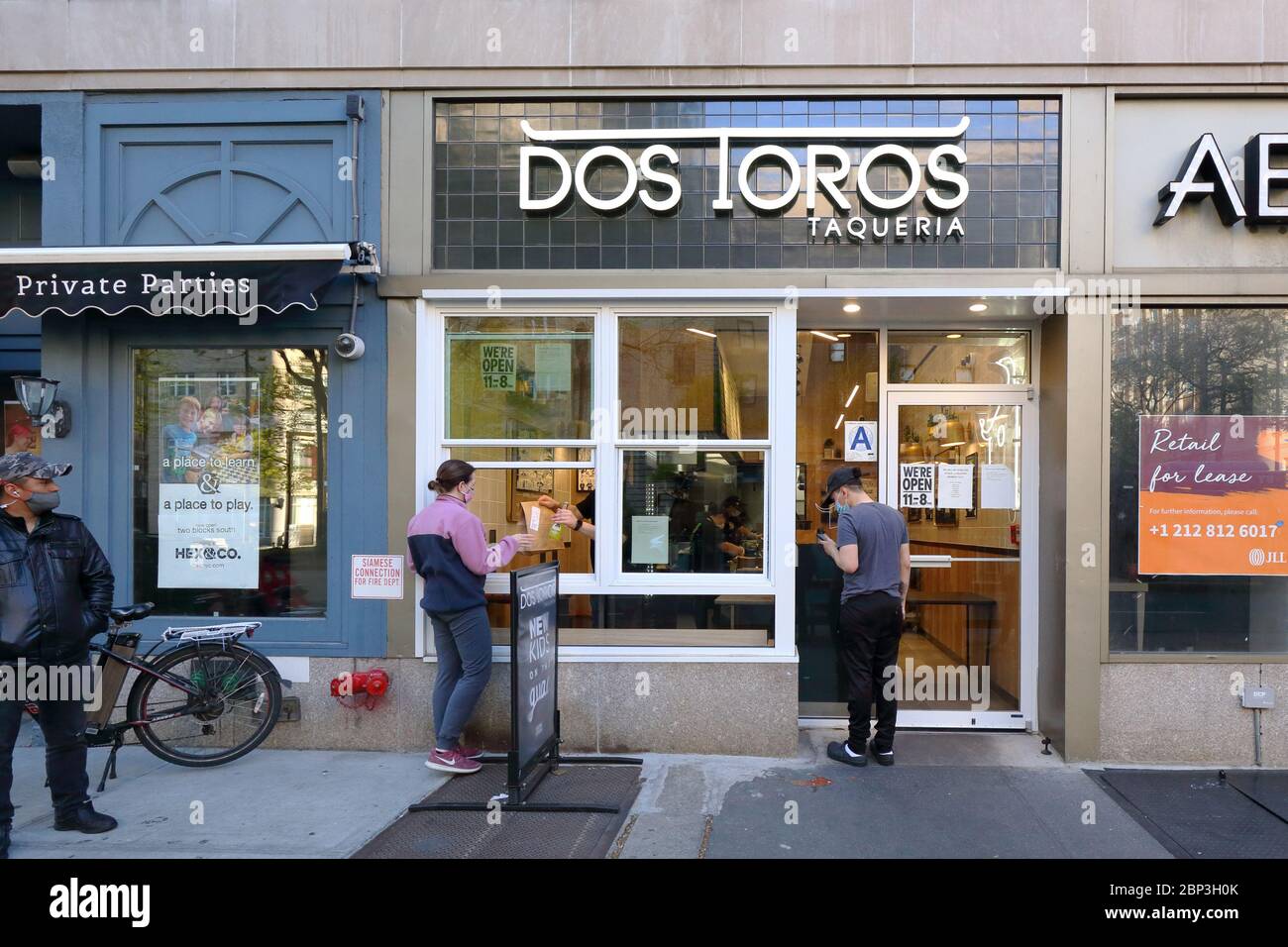 Una persona ritira un ordine presso un ristorante Dos Toros a New York aperto per affari per il prelievo e la consegna solo durante la crisi del coronavirus Foto Stock