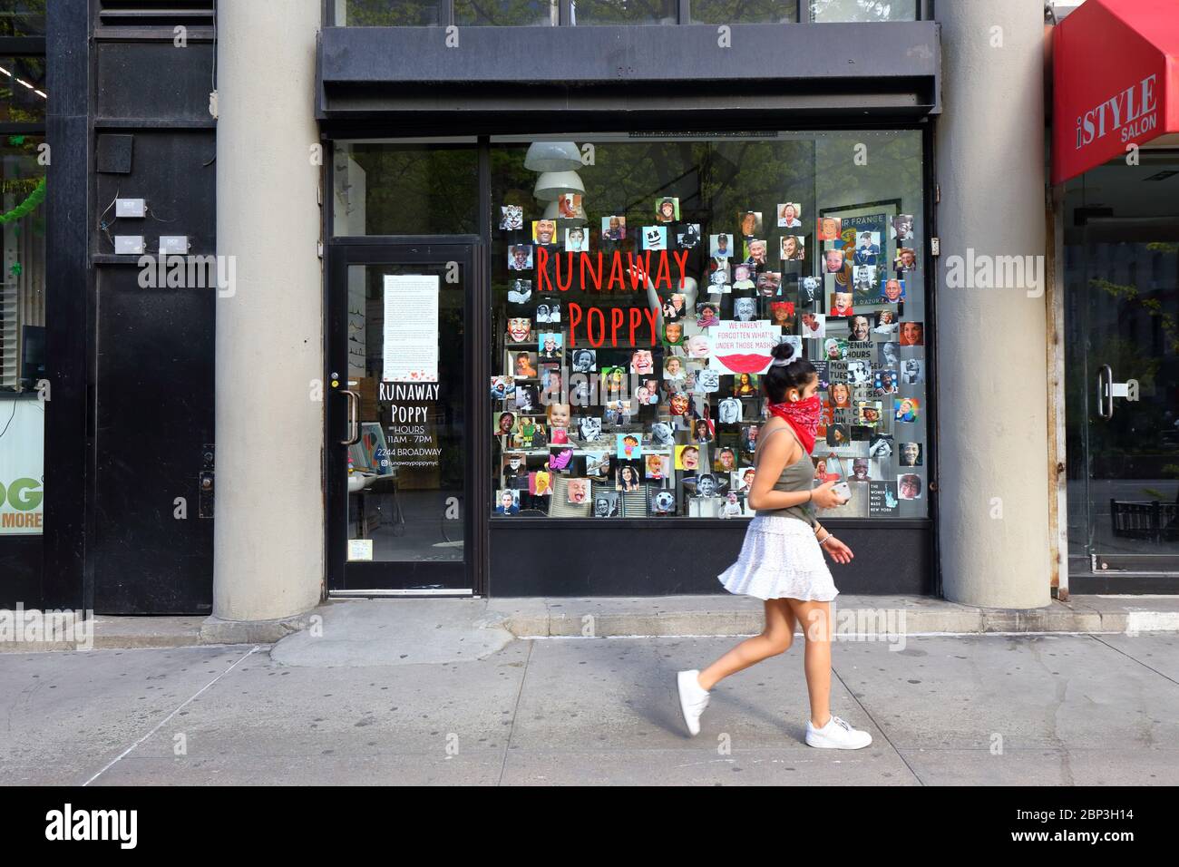 Una persona cammina da Runaway Poppy a New York con le immagini di volti sorridenti appesi alla finestra durante la crisi del coronavirus. Un segno dice 'non abbiamo Foto Stock
