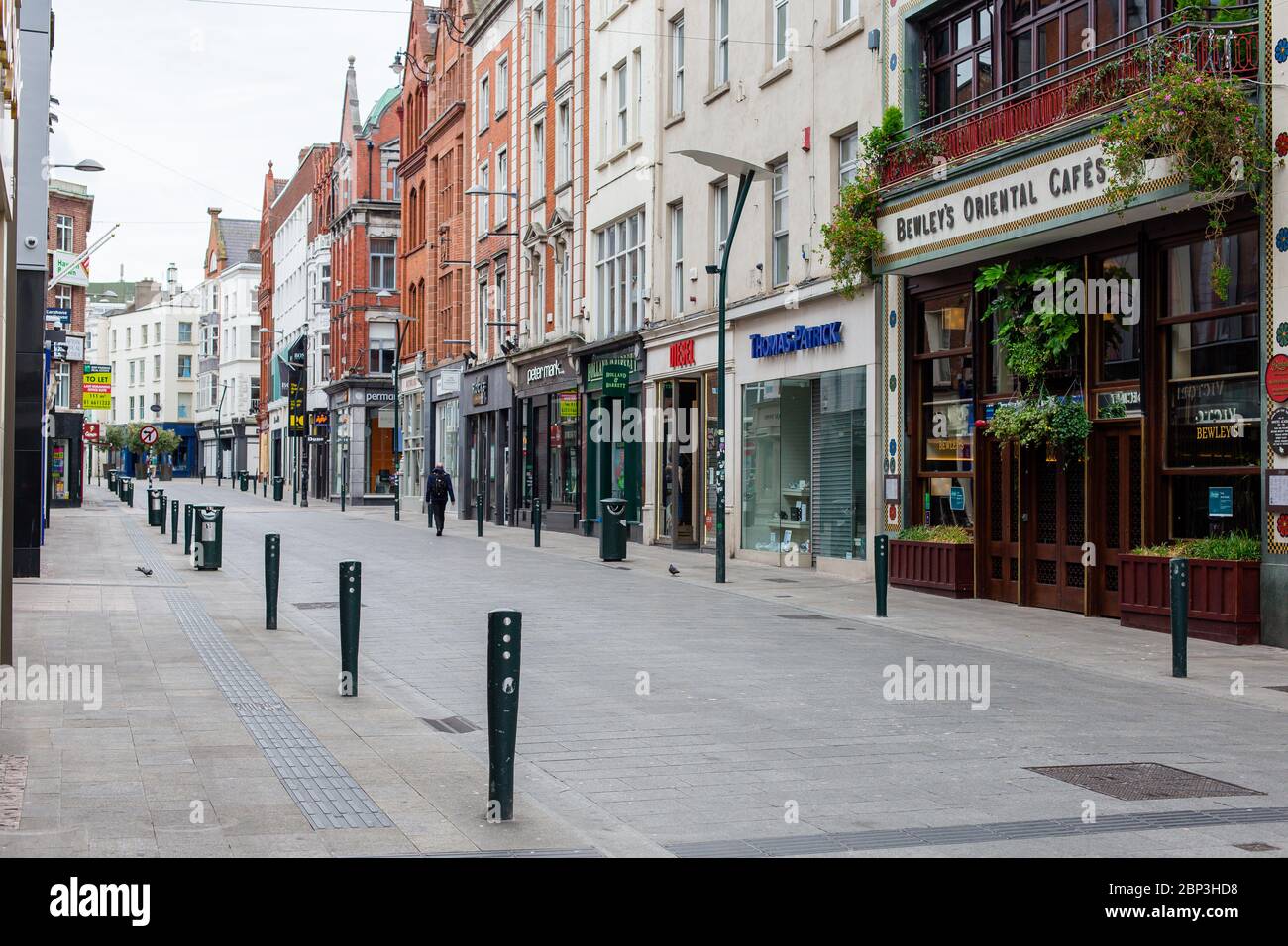 I pedoni passeggiano attraverso una strada deserta Grafton nel centro di Dublino, mentre i negozi rimangono chiusi a causa di restrizioni pandemiche di coronavirus. Foto Stock