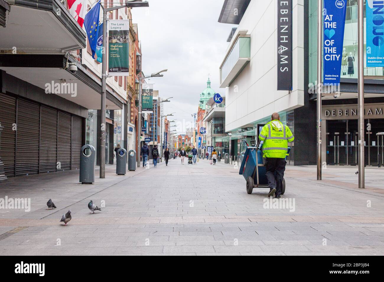 Il lavoratore della manutenzione stradale del consiglio della contea cammina attraverso la deserta Henry Street a Dublino Irlanda, mentre il calco precipita a causa della pandemia del coronavirus. Foto Stock