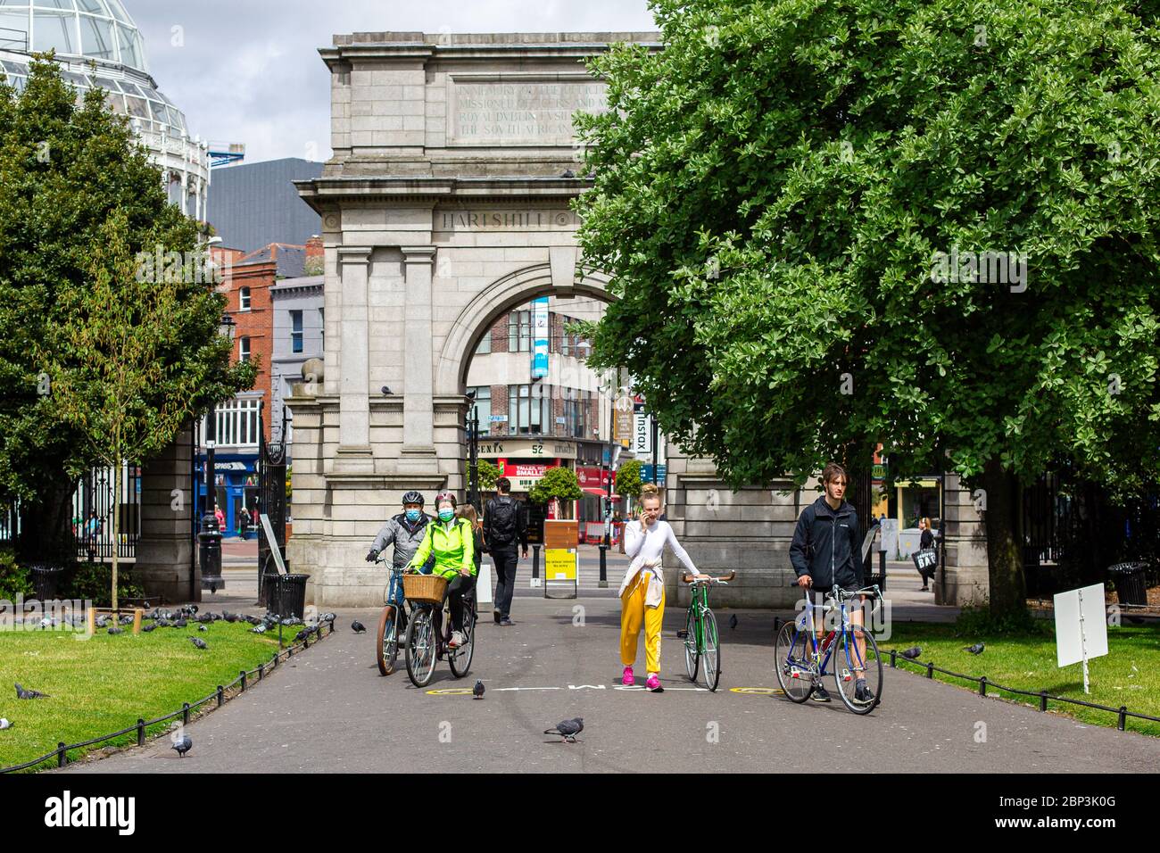 Persone con biciclette che indossano maschere per il viso che entrano nel Parco Verde di Santo Stefano`s a Dublino, che aderiscono alle regole di distanza sociale durante la pandemia del covid-19. Foto Stock
