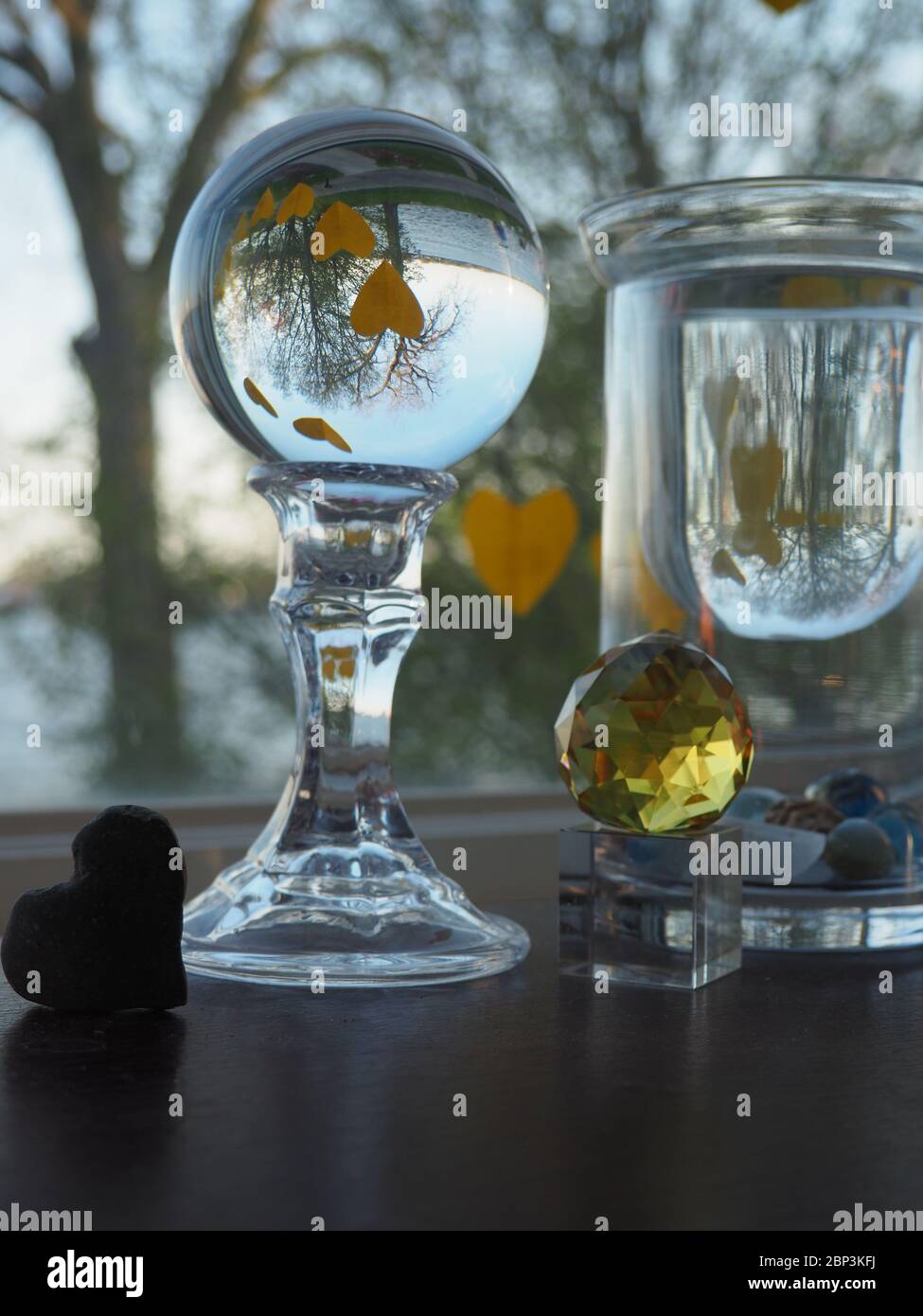 Cuori gialli a forma di un volto Smiley riflesso in una sfera di vetro Foto Stock