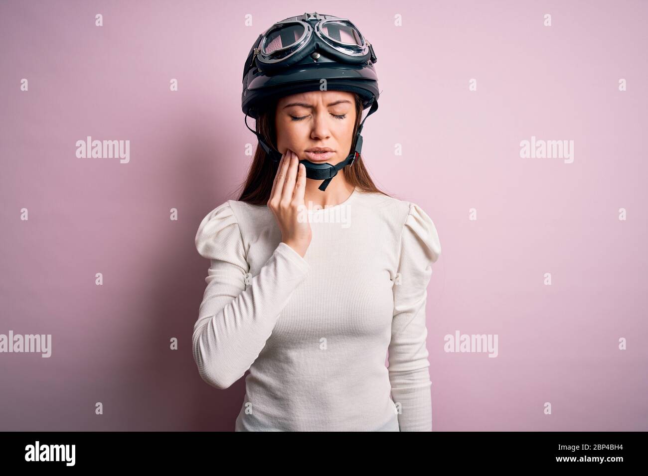 Giovane bella motociclista donna con occhi blu che indossa casco moto su  sfondo rosa che tocca bocca con mano con espressione dolorosa a causa di  Foto stock - Alamy