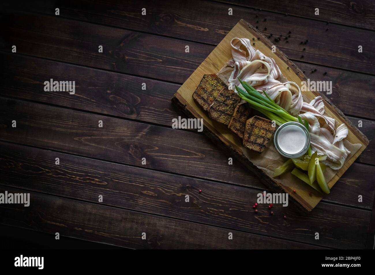 Cetrioli in barile, lardo a fette, pane fritto e cipolle sulla tavola di legno su sfondo grigio. Composizione piatta. Spazio libero per il testo Foto Stock