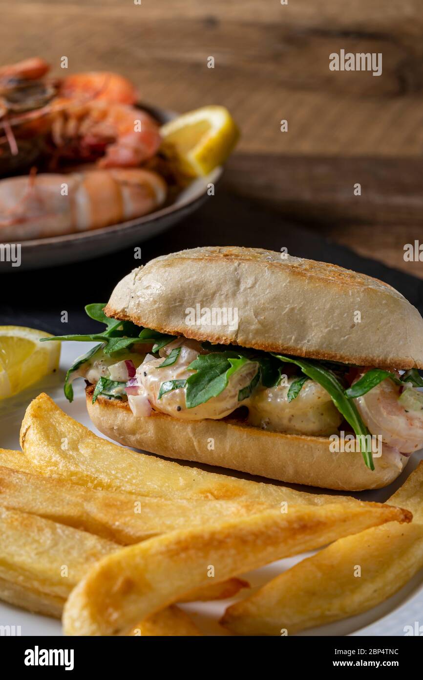 Insalata di gamberi su involtino di hoagie con rucola e patate fritte in forno in casa. Foto Stock