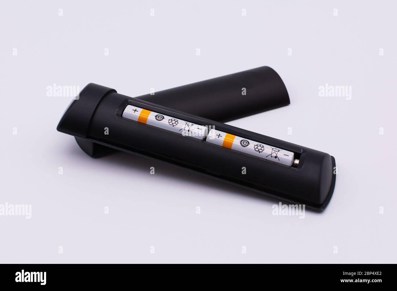 Simboli internazionali di riciclaggio su due batterie inserite nel telecomando. Foto Stock
