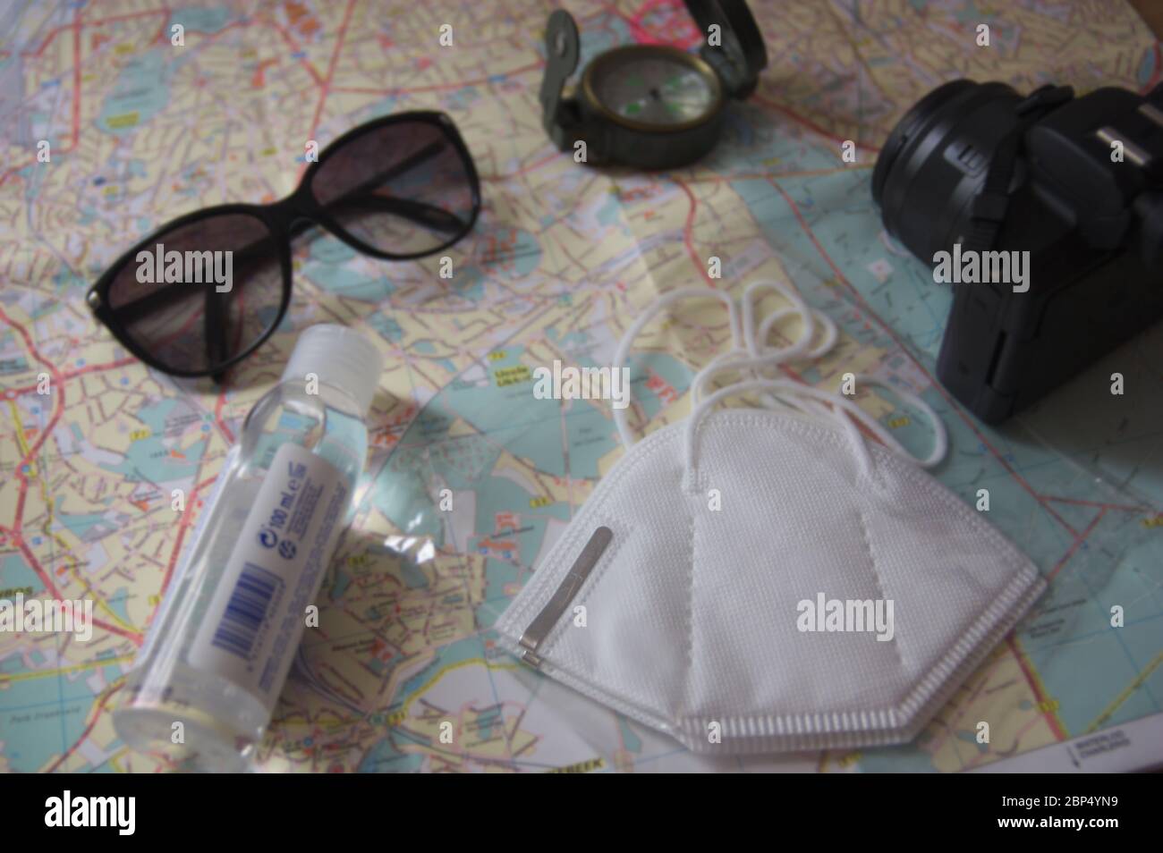 Disposizione piana di un tavolo dove su una mappa vediamo alcune maschere, idrogel per le mani, occhiali, una bussola e una macchina fotografica, gli elementi necessari per ogni turista Foto Stock