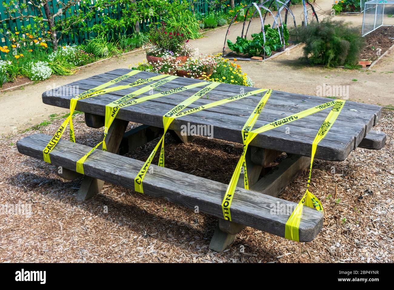 Tavolo da picnic in legno nel parco pubblico protetto con nastro giallo per barricata per evitare l'uso accidentale durante l'ordine di soggiorno a casa al coronavirus, covid-19 Foto Stock