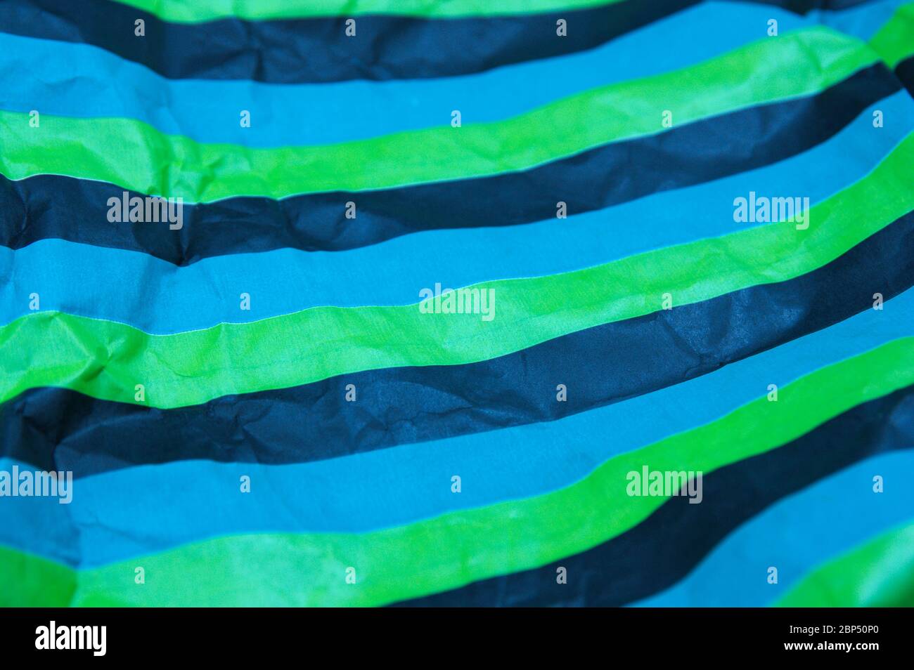 Primo piano di una carta a strisce parallele di colori nero, verde, blu che è leggermente stropicciata Foto Stock
