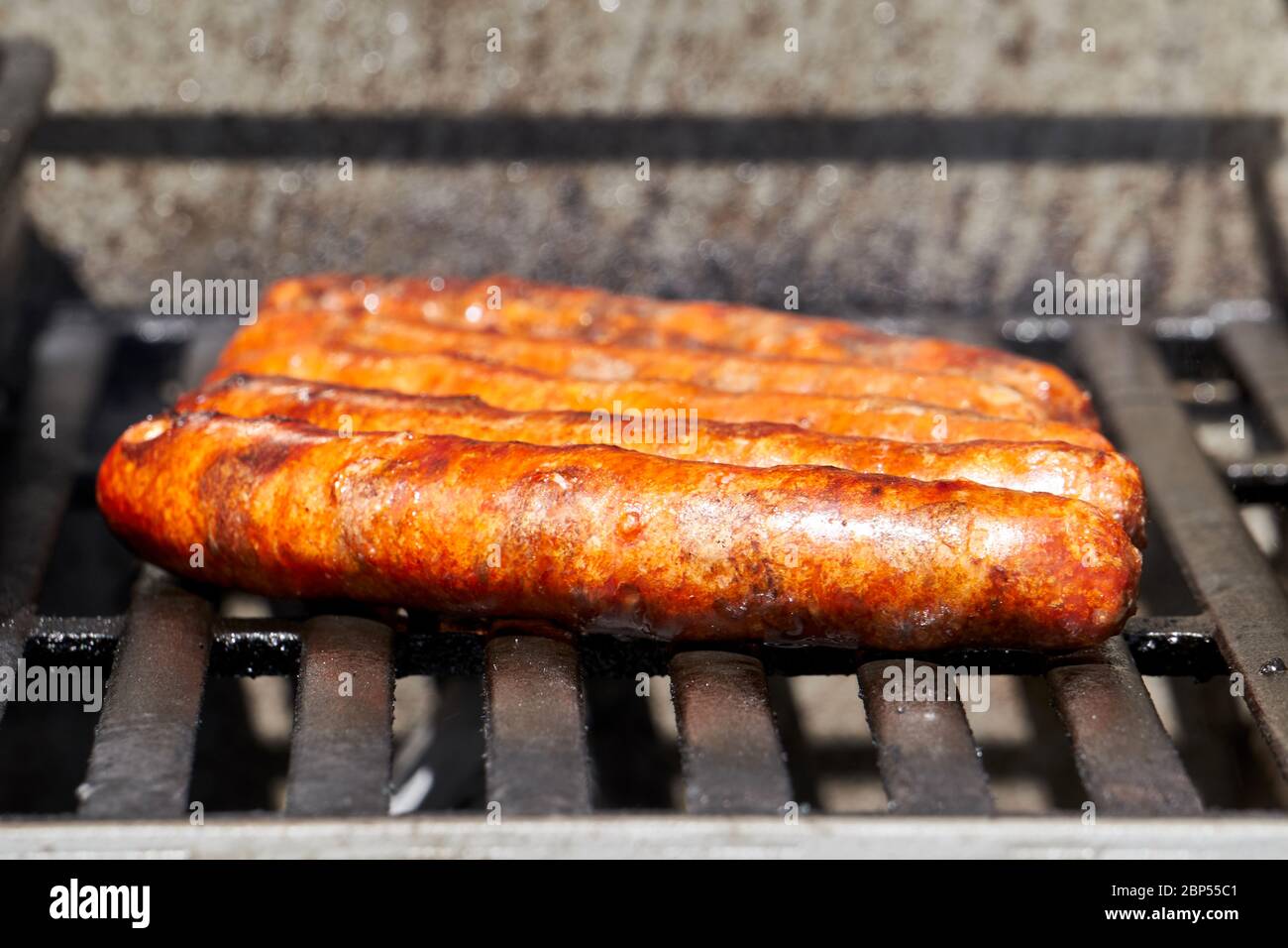 Salsicce merguez grigliate su un barbecue a gas durante UNA bella giornata estiva Foto Stock