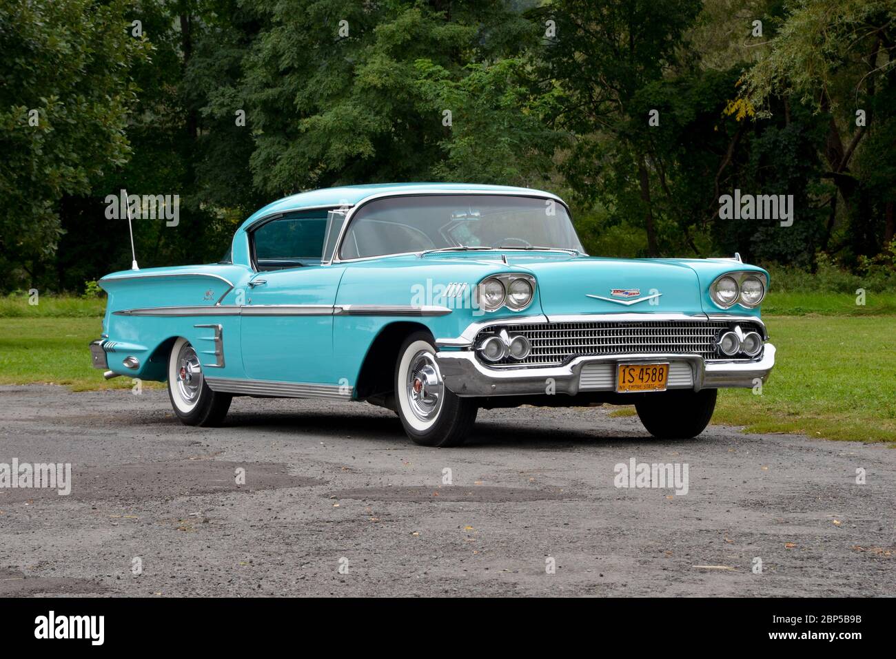 Turquoise 1958 Chevrolet Impala coupé tre quarti di vista frontale contro gli alberi Foto Stock