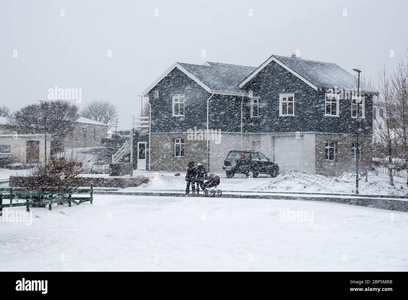 Famiglia non riconosciuta con bambini che camminano all'esterno durante la tempesta di neve pesante nel villaggio di Vik in Islanda Foto Stock