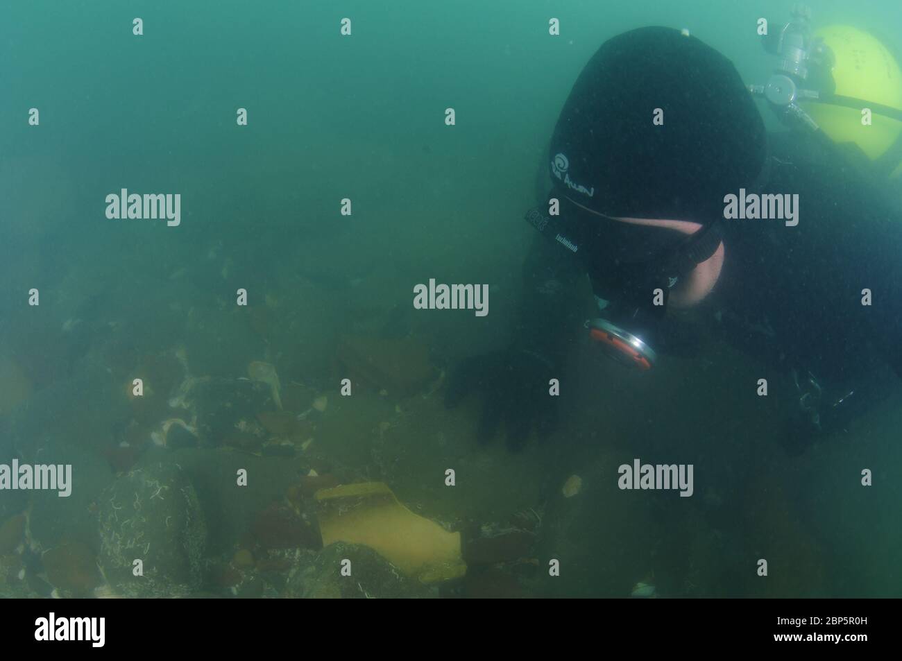 Subacqueo respiratore da regolatore vintage con staffa in metallo cromato su fondo roccioso in acqua torbida. Foto Stock