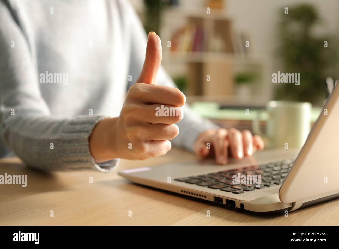 Primo piano delle mani della donna con i pollici che usano il laptop di notte a casa Foto Stock