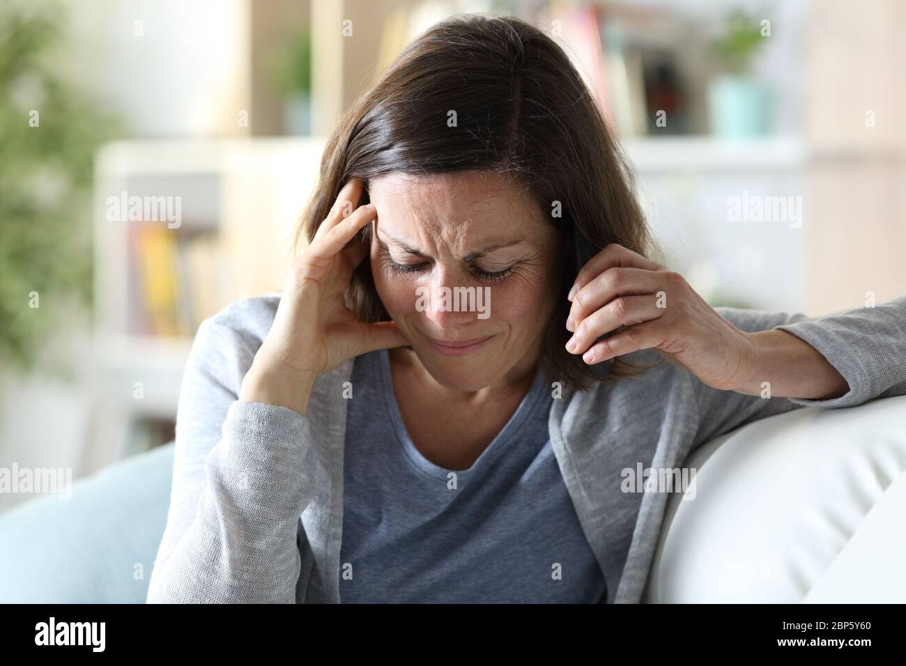 Triste donna di mezza età che chiama su smartphone seduto su un divano a casa Foto Stock