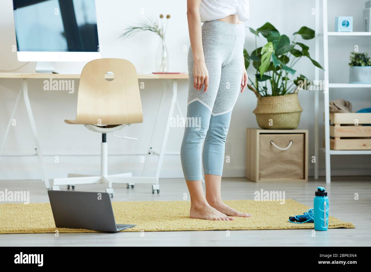 Vista in sezione bassa a donna irriconoscibile in piedi su tappeto a casa pronto per il lavoro online, spazio di copia Foto Stock