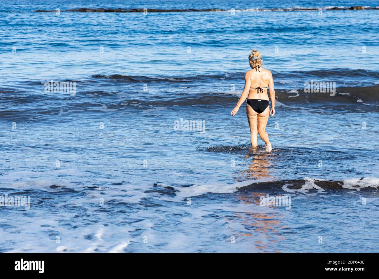 Donna entra in mare per una nuotata illecita durante la prima fase di de-escalation del Covid 19, coronavirus, stato di emergenza, Fanabe, Costa Adeje, Foto Stock