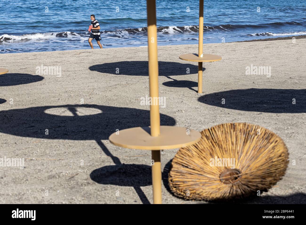 La gente ha intravisto tra gli ombrelloni inutilizzati facendo esercizio a piedi sulla spiaggia di Playa Fanabe durante la fase uno di de-escalation del Covid 1 Foto Stock