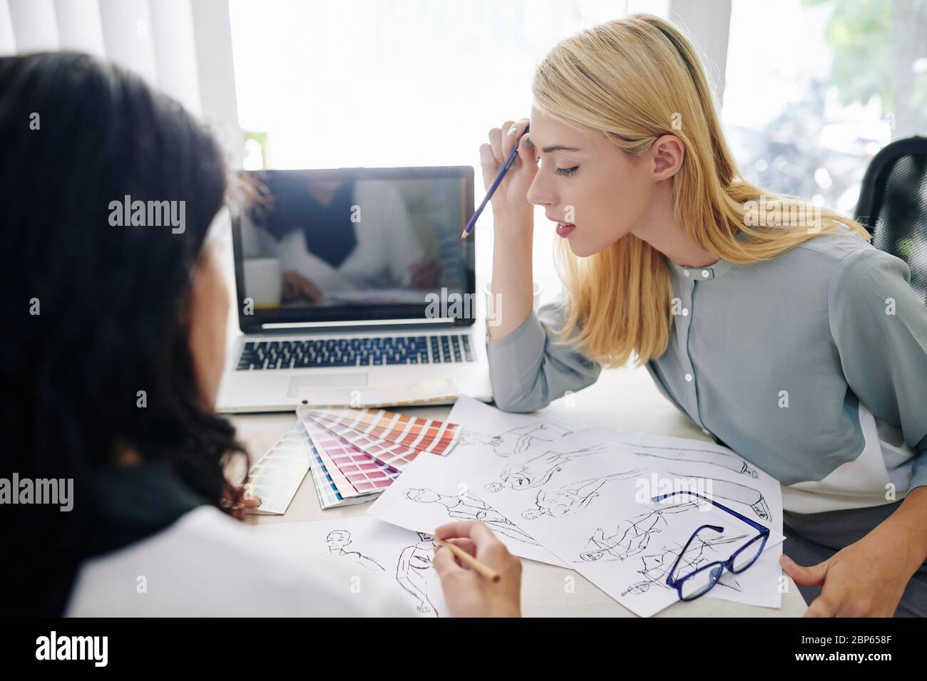 Giovani stilisti femminili che lavorano su nuove collezioni e scelgono lo schema di colori Foto Stock