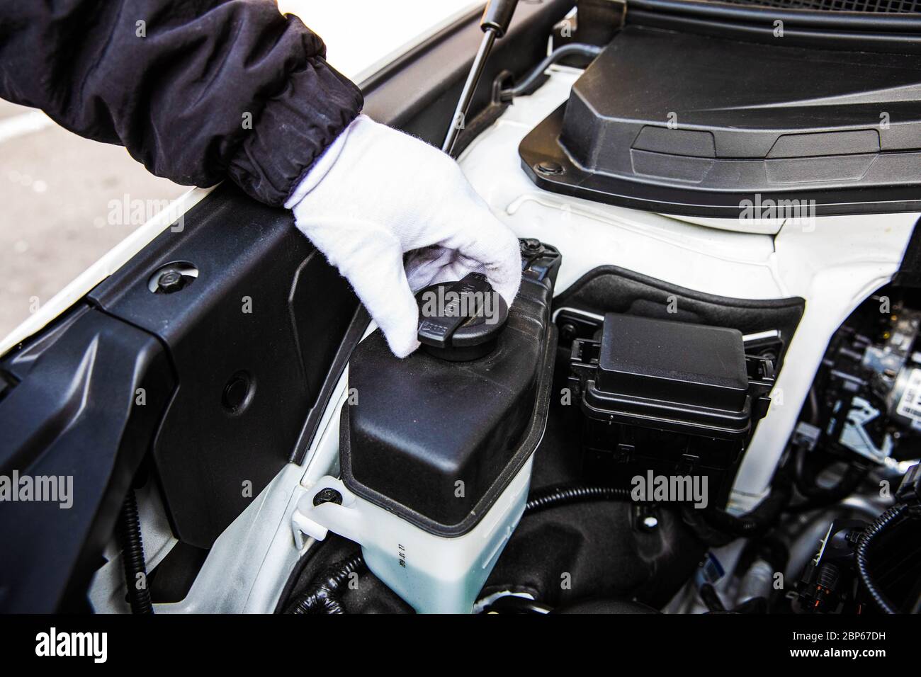 Aprire manualmente il tappo del serbatoio del liquido di raffreddamento del motore di un'auto. Foto Stock