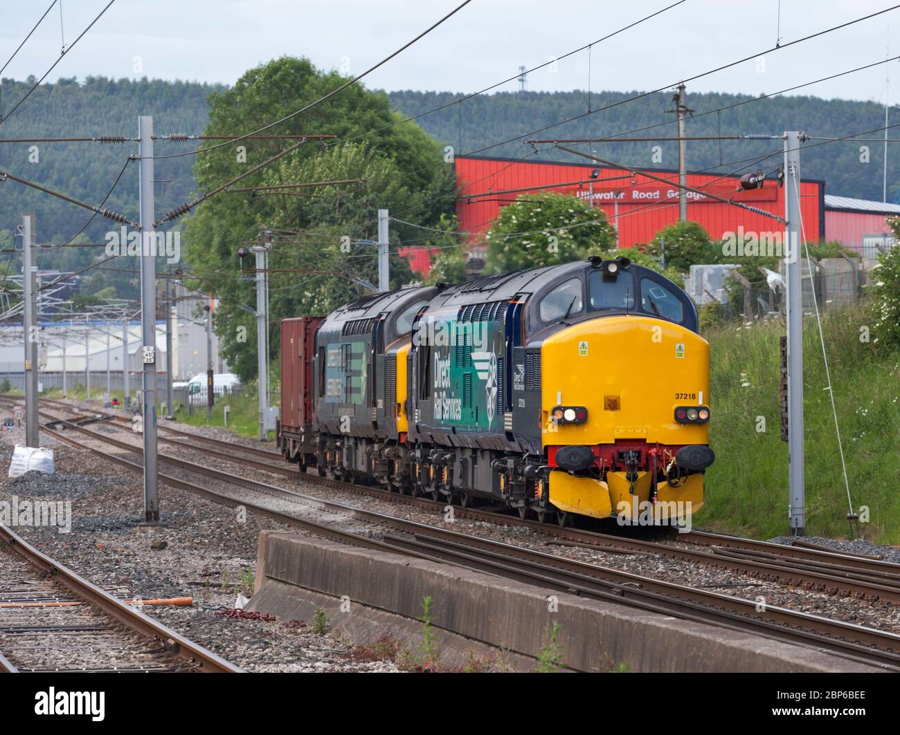 2 servizi ferroviari diretti locomotive classe 37 37218 + 37612 passando Penrith sulla linea principale della costa occidentale con un contenitore di rifiuti nucleari di basso livello Foto Stock