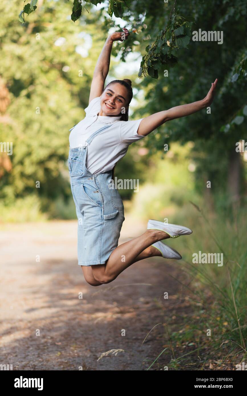 La ragazza in tuta salta con le gambe incrociate. Foto Stock