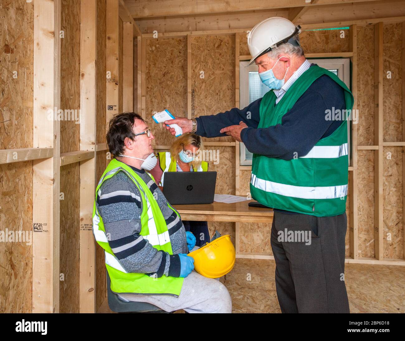 Carrigaline, Cork, Irlanda. 18 maggio 2020.il primo giorno della prima fase con l'alleggerimento delle restrizioni Covid-19 l'addetto alla sicurezza Michael o'Sullivan controlla la tempera di uno dei lavoratori assistiti da Caroline o'Keffee nel cantiere Astra a Janeville, Carrigaline, Co. Cork, Irlanda. - credito; David Creedon / Alamy Live News Foto Stock