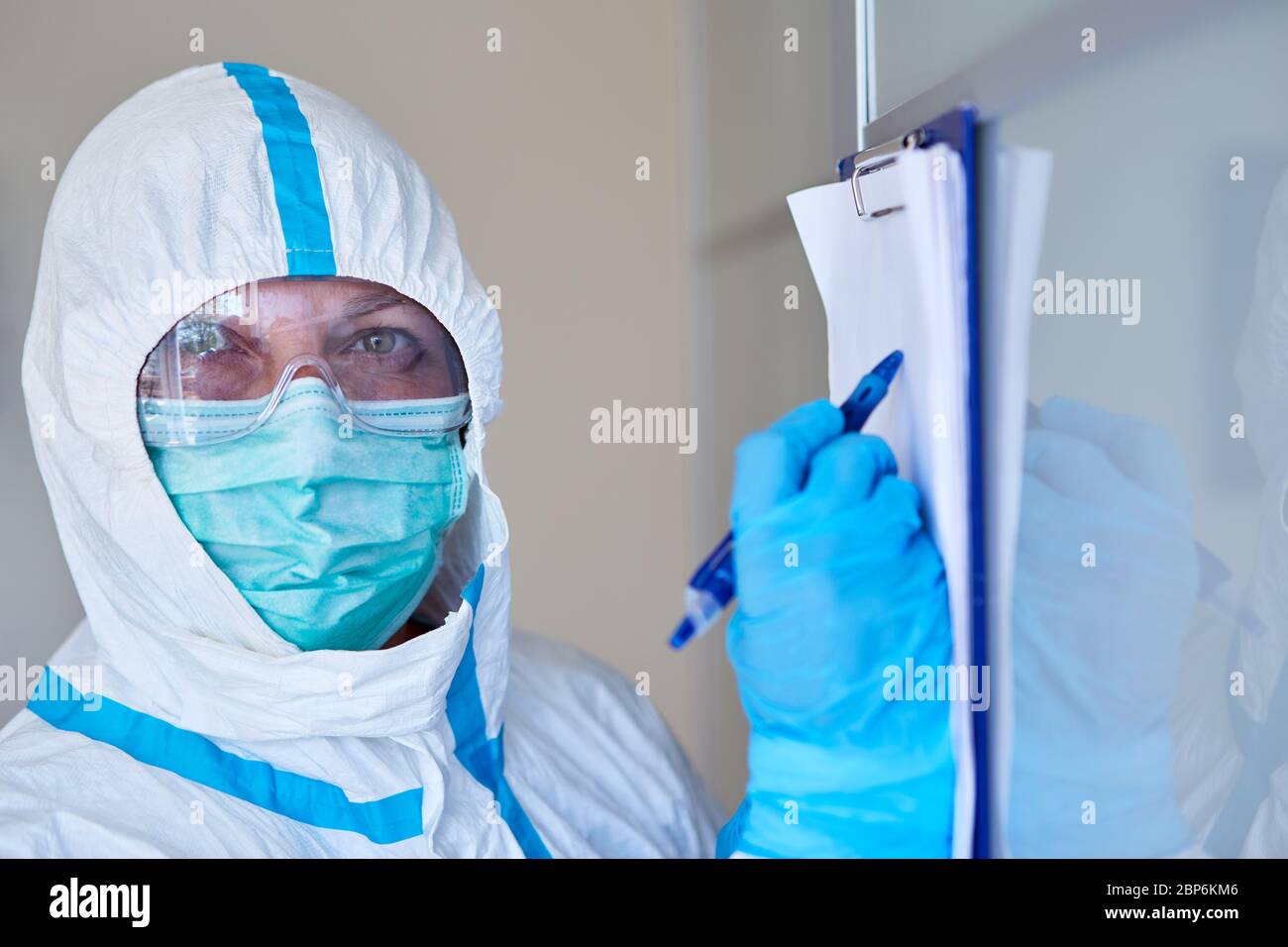 Personale addetto alla cura o alla ricerca di un contenitore con elenco visitatori o monitoraggio dei contatti a causa di una pandemia di coronavirus in clinica o in casa di cura Foto Stock