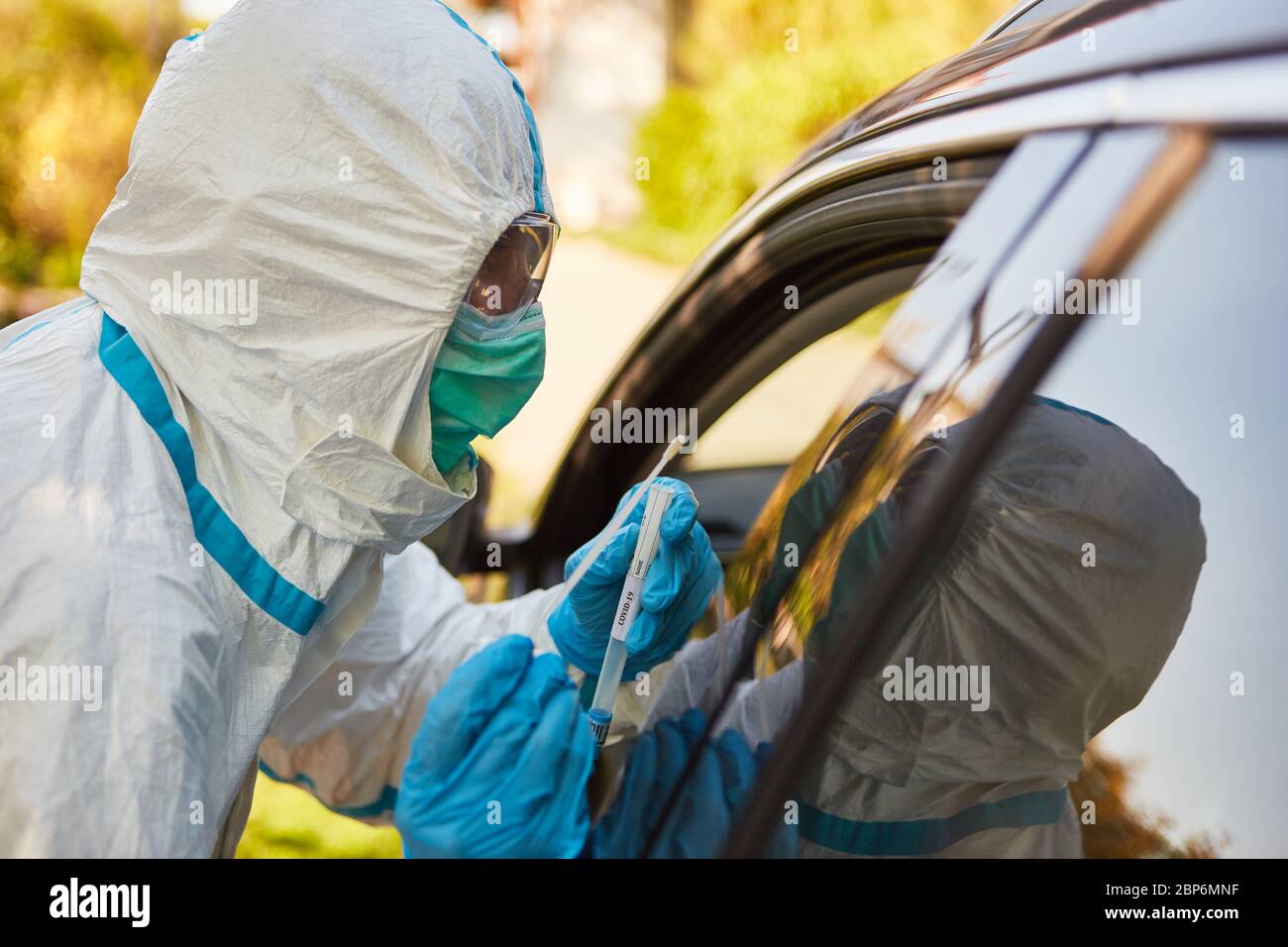 Test del virus Corona tramite scout di contenimento dal reparto sanitario con un tampone alla gola nella stazione di test drive-in Foto Stock