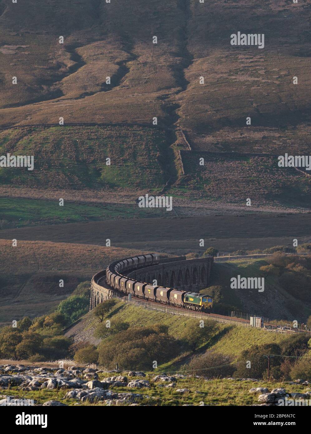 Locomotiva Freightliner classe 66 66510 che corre via dal viadotto Ribblehead con un treno a carbone allegro e rotondo con la campagna che lo sovrasta Foto Stock