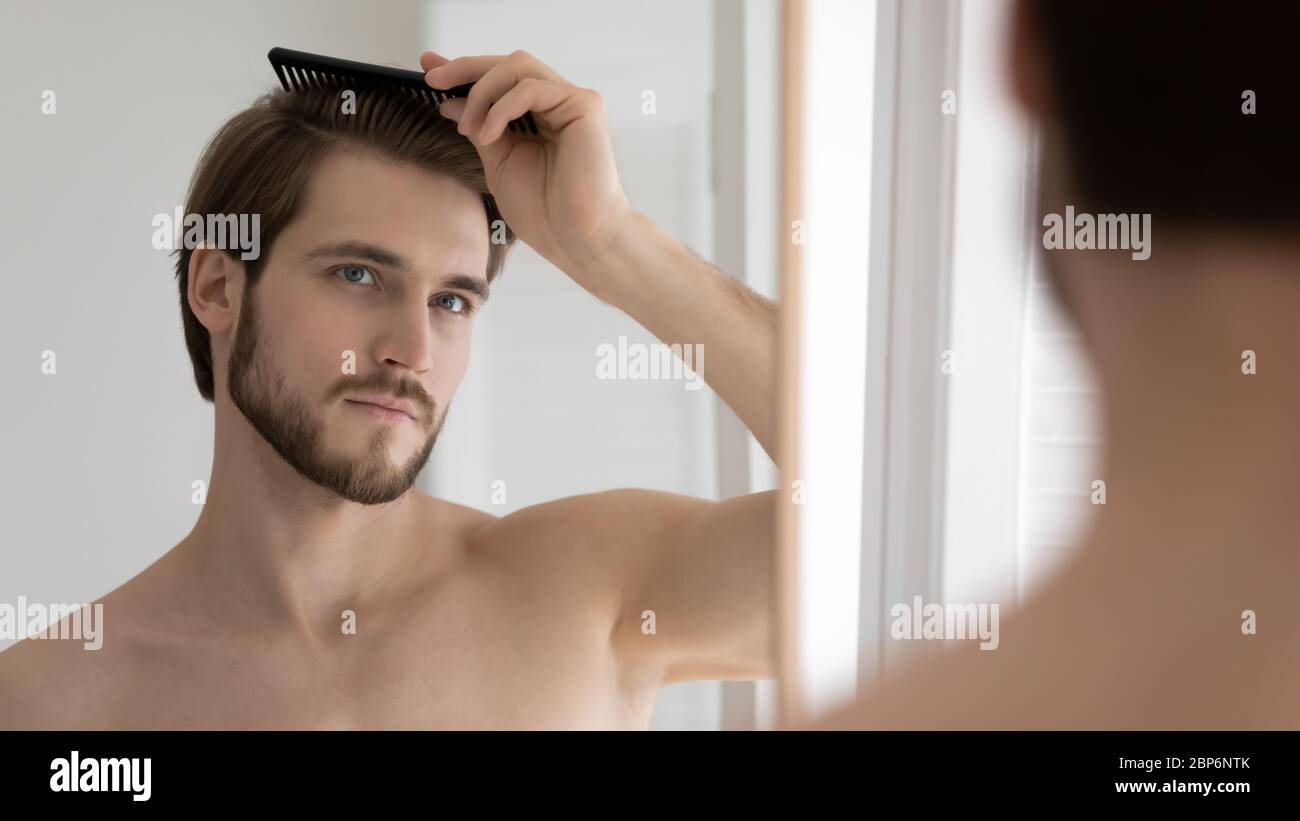 Giovane uomo caucasico spazzola capelli stile in bagno Foto Stock