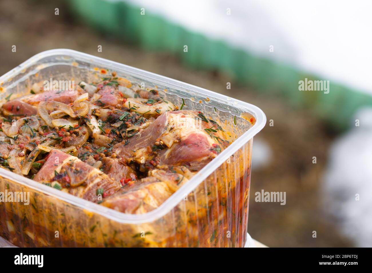 Carne di maiale cruda e succosa marinata in contenitore di plastica. Cibo fresco preparato per barbecue. Cucina estiva all'aperto Foto Stock