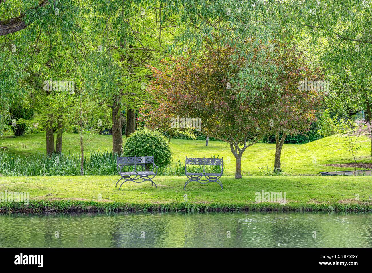 Tranquillo giardino con un fiume e un posto a sedere Foto Stock