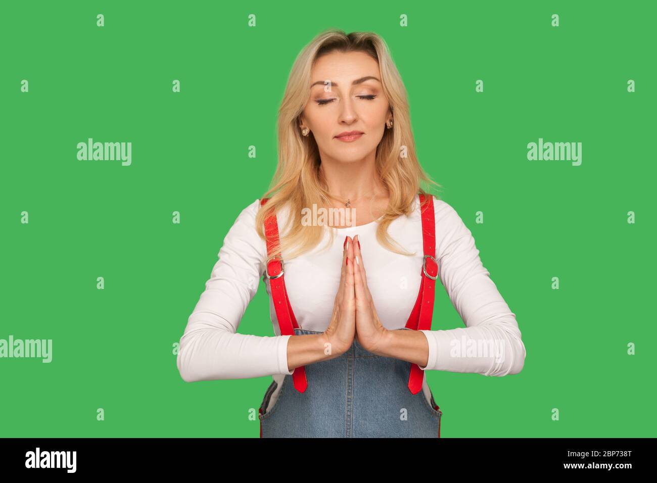 Mente pacifica, pratica yoga. Ritratto di bella donna adulta calma in tute eleganti meditando con il gesto di namaste, sentendosi concentrata e rel Foto Stock