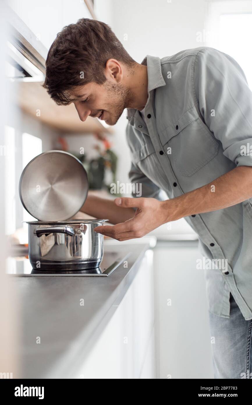 Sorridente giovane impiegato seduto alla sua scrivania e indicando voi Foto Stock